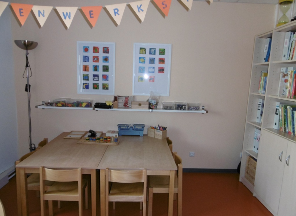 Auf der rechten Seite steht ein Regal mit Büchern. An einer Sitzgruppe haben die Kinder die Möglichkeit zu malen und zu spielen.