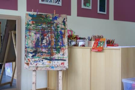 Schreibwerkstatt und Atelier der Kita Niederscheld: Eine bunt bemalte Leinwand und auf den Schränken dahinter jede Menge Stifte und Farben